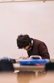 A high school student studying and solving problems in a classroom setting.